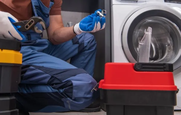 Hombre con heramienta componiendo una lavadora