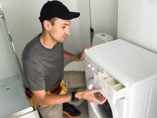 hombre reparando una secadora blanca